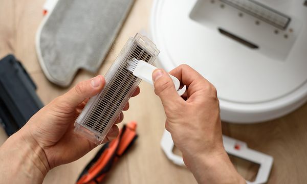 Person i færd med at rense et filter fra en robotstøvsuger 