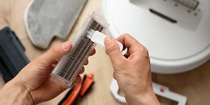 Person i færd med at rense et filter fra en robotstøvsuger 