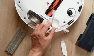 En person der renser sensorerne på en robotstøvsuger