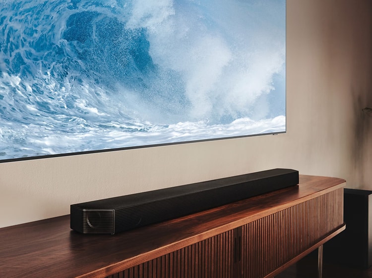 Samsing Q810B Soundbar med tilhørende subwoofer på et TV-møbel under et TV i en stue 