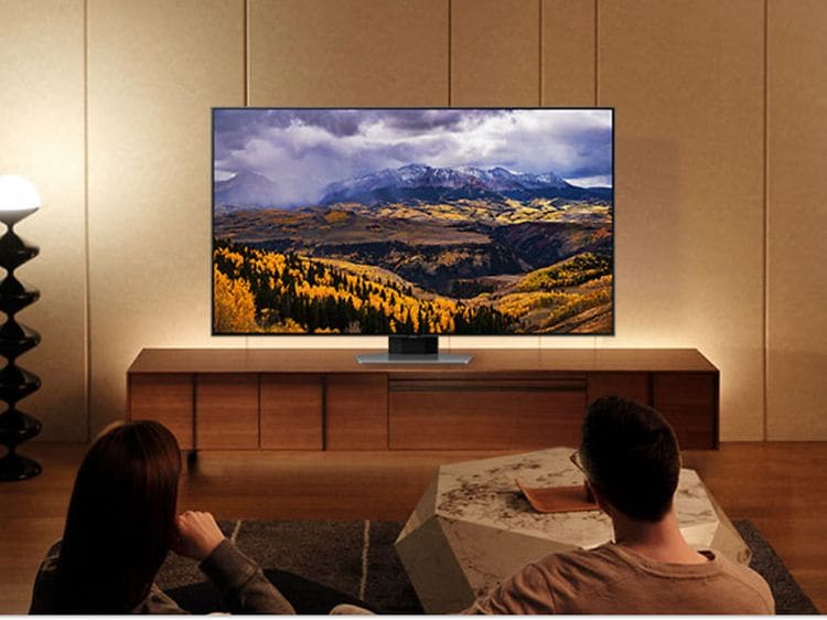 Et par, der sidder i en sofa og nyder Samsung TV's stærke farver for en rigere visning