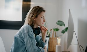 Kvinde med hovedtelefoner foran en PC