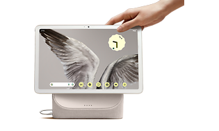 En hånd, der rækker ud efter Google Pixel-tabletten, der viser et billede af fuglevinger