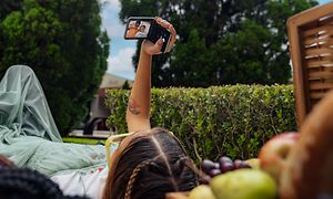 Kvinde der ligger med en Motorola Razr, halvt sammenfoldet i videotilstand og tager selfie af sig selv