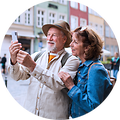 Ældre par, der står på gaden og tager billede med deres smartphone
