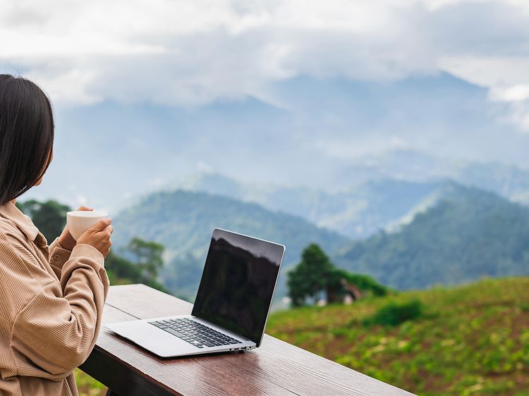 Kvinde med en bærbar computer med udsigt over naturen og bjergene