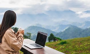Kvinde med en bærbar computer med udsigt over naturen og bjergene