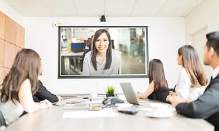 Et mødelokale med ansatte der deltager i et hybridmøde, både fysisk og digitalt