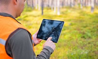 Mand tjekker planer på sin tablet i skoven