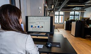 En forretningskvinde, der sidder på et kontor og arbejder foran sin computer