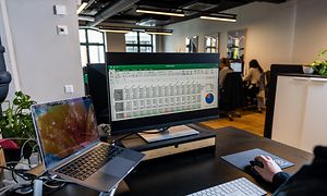 En person der sidder og arbejder på et kontor og har Excel åbent på sin computer