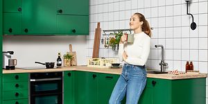 Kvinde står med et kop foran hendes grønne køkken