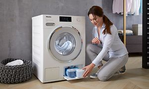 Miele vaskemaskine med TwinDos og en kvinde ved siden af fylder vaskemiddel