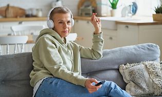 Kvinde med hovedtelefoner sidder i sofa og ser TV
