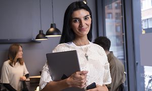 Smilende kvinde med en tablet på et kontor