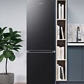 Samsung køleskab og fryser i et gråblåt køkken med en plante ved siden af