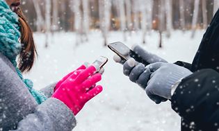 To personer bruger smartphones udenfor i sneen