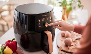 Philips airfryer og en hånd, der presser på en knap