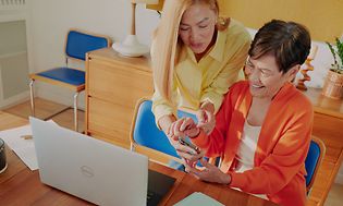 To kvinder foran en computer og smartphone