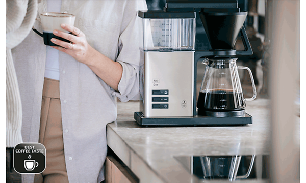 Melitta One kaffemaskine på et køkkenbord og en person der drikker kaffe