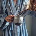 Giv glæde på mors dag: Kvinde i badekåbe med en kop kaffe