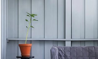 Vægmonteret terrassevarmer over en grøn plante og en sofa