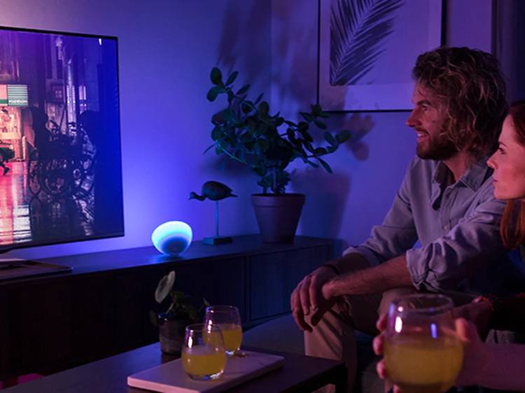 fire personer ser fjernsyn med omgivende lilla og blåt Philips Hue- lys