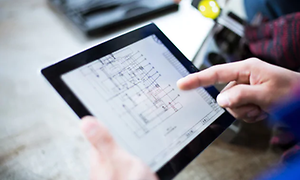 En finger peger på en byggeplan på en tablet