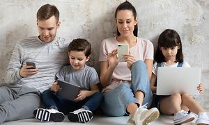 En familie, der kigger på deres mobile enheder