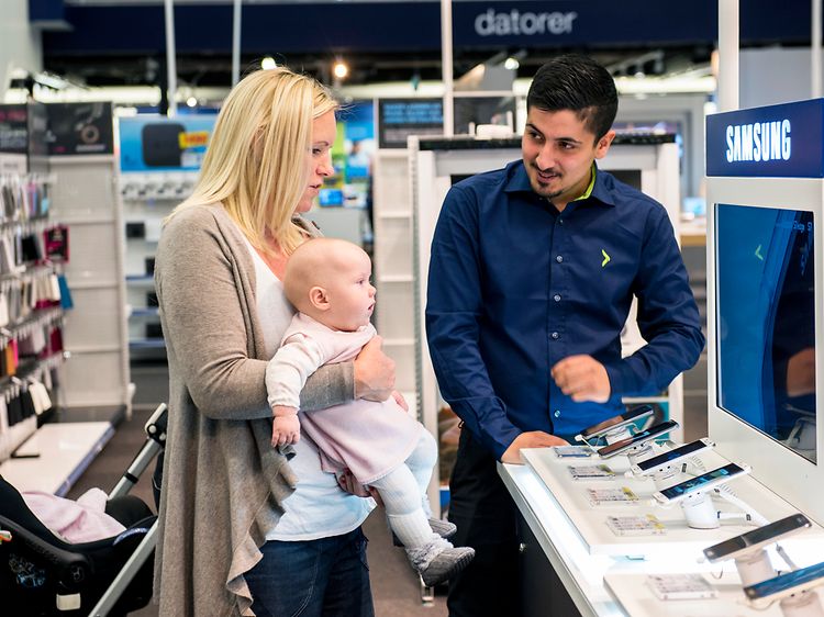 Mor med baby får hjælp fra en medarbejder i Elgiganten butikkens telefonafdeling