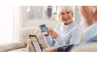 Ældre dame med hendes smartphone der smiler