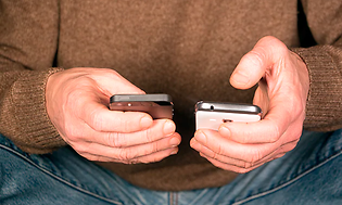Mand der holder to telefoner