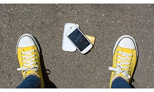 En telefon der er blevet tabt og gule sko