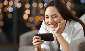 Pige der kigger på sin telefon og smiler