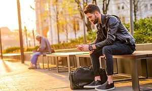 To personer på en bænk der kigger på deres telefoner