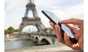 Person der holder telefon med Eiffeltårnet i baggrunden