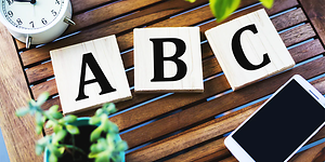 Bogstaverne ABC på et bord med en telefon tæt på