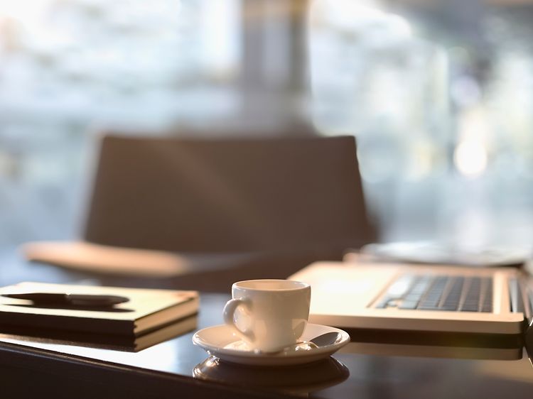 en kop kaffe foran en macbook på et kontor