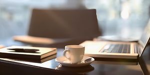 en kop kaffe foran en macbook på et kontor