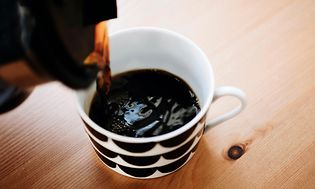 sort kaffe bliver hældt i et krus