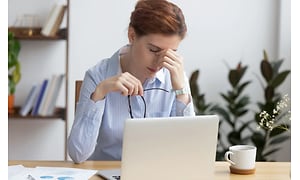 kvinde med trætte øjne arbejder på sin computer