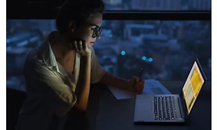 Kvinde der bruger Lenovo Thinkbook i et mørkt rum
