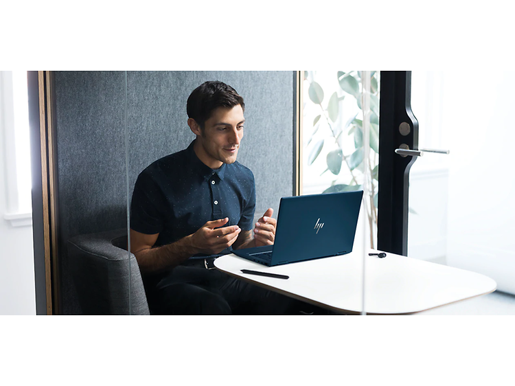 man sidder ved et bord og foretager et videoopkald fra sin hp bærbare computer