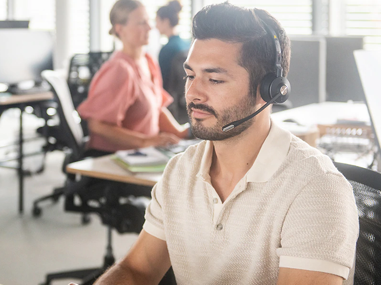 mand på et åbent kontor med sit headset