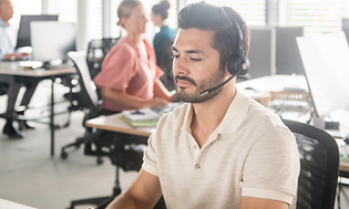 mand på et åbent kontor med sit headset