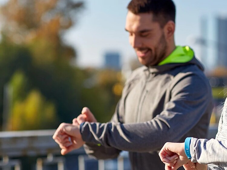 kvinde og mand justerer på deres smart watch og aktivitetsur under en løbetur