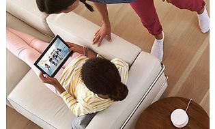 en pige ser en video på sin tablet ved siden af en voksen