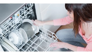 Kvinde der sætter service i opvaskemaskinen