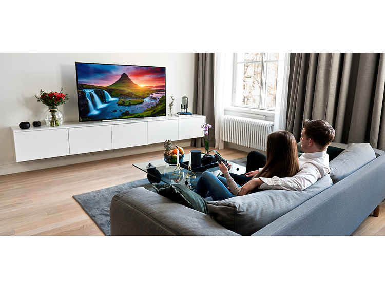 par sidder i en sofa og ser TV med stærke farver