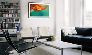 Stue med sort sofa, hvidt bord og grønt maleri